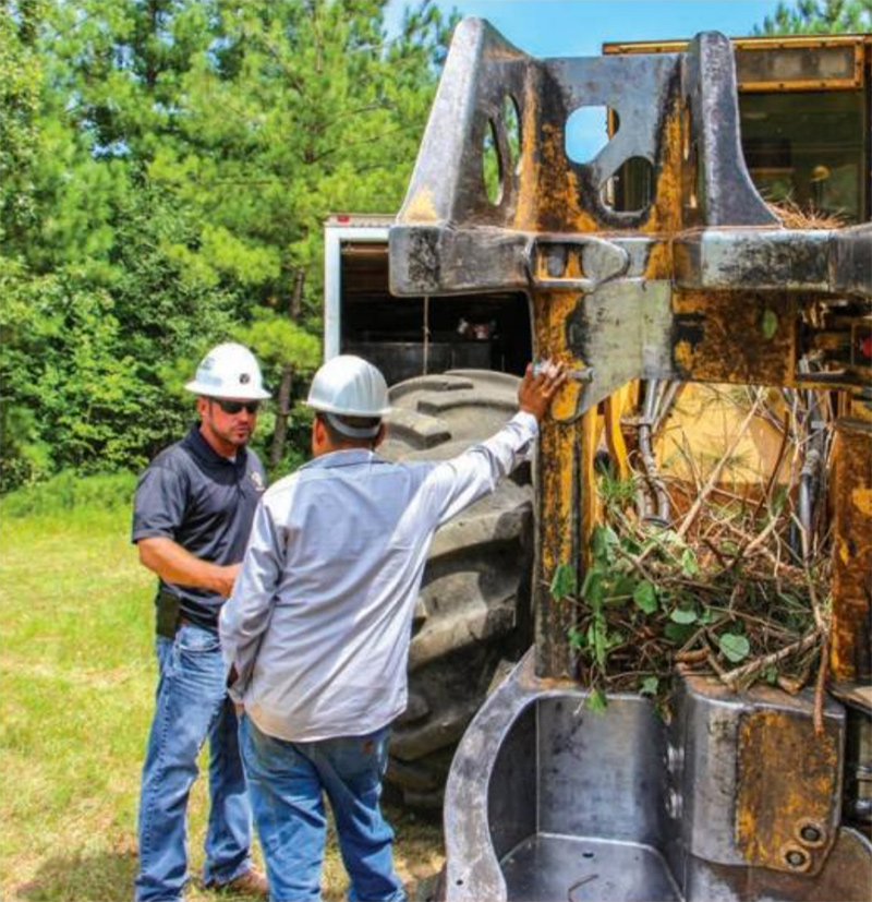 photo of Adam Wilbourne talking with an employee standing beside heavy equipment